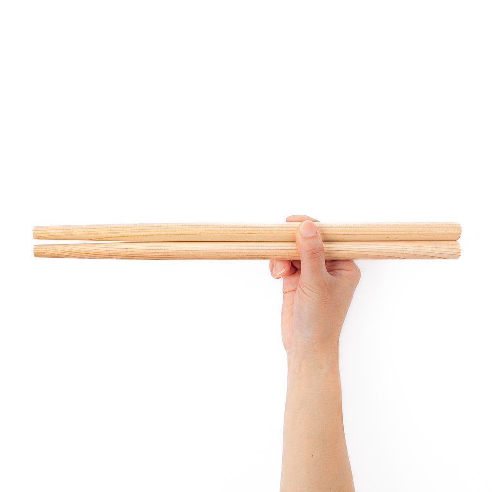 A pair of thick Japanese tempura cooking chopsticks made from light natural wood showcasing a minimalist and sturdy design