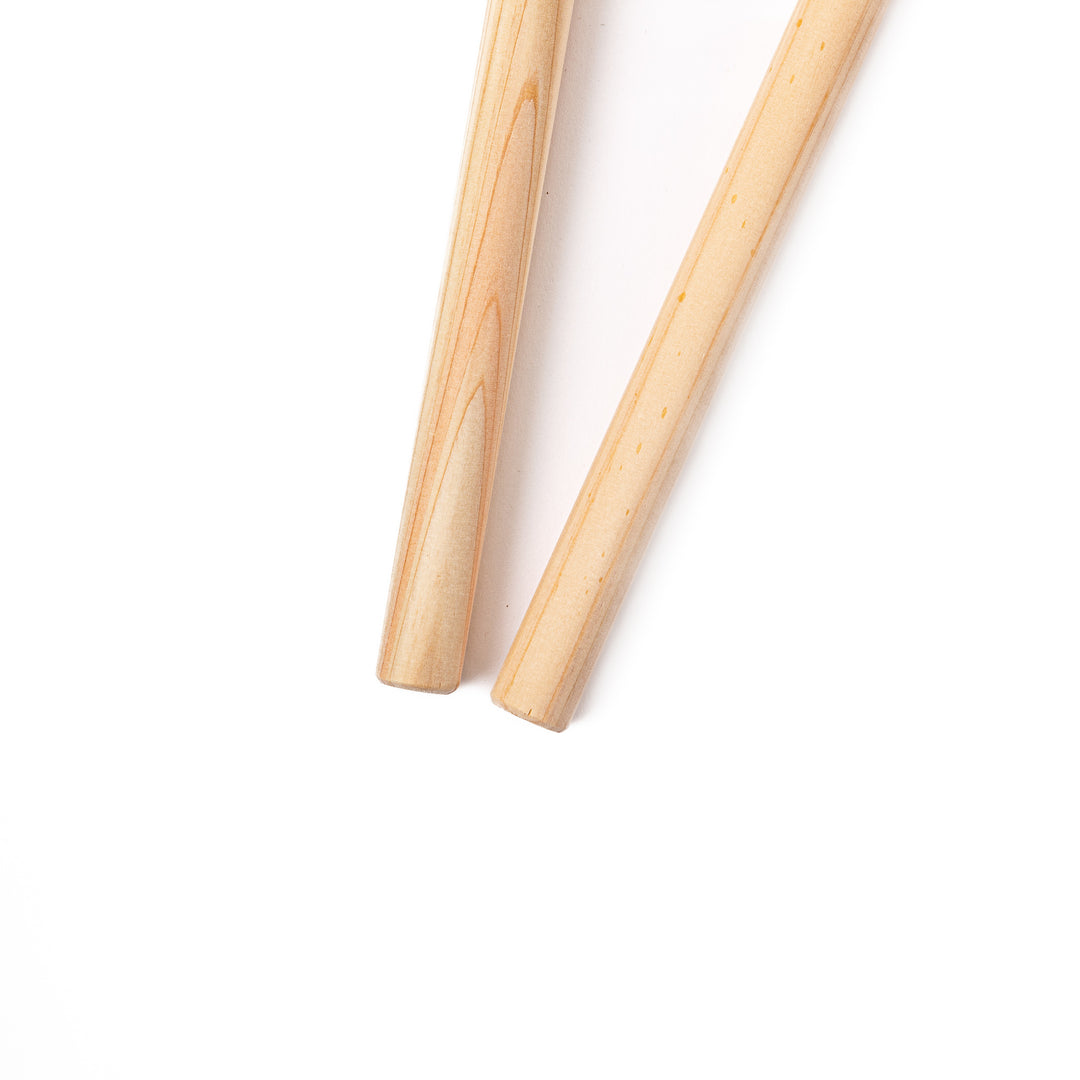 A pair of thick Japanese tempura cooking chopsticks made from light natural wood showcasing a minimalist and sturdy design