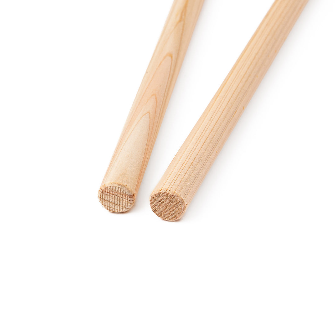 A pair of thick Japanese tempura cooking chopsticks made from light natural wood showcasing a minimalist and sturdy design