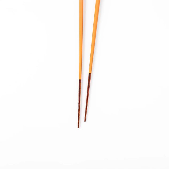 Pair of tangerine orange Japanese traditional color bamboo chopsticks with fine tips for a precise and elegant dining experience
