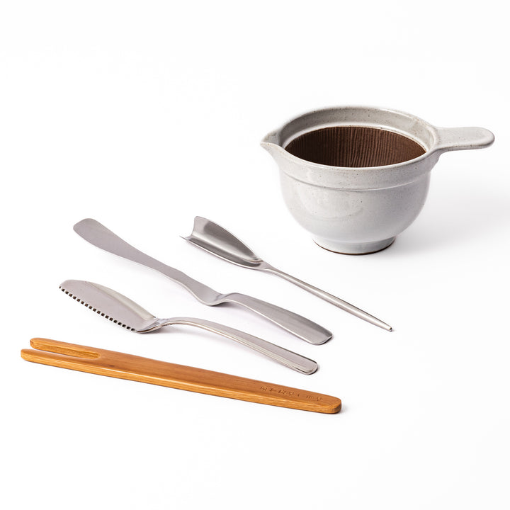 Japanese breakfast set featuring a ceramic suribachi mortar and pestle bowl with stainless steel butter knives and bamboo utensil, ideal for preparing and serving traditional morning dishes.