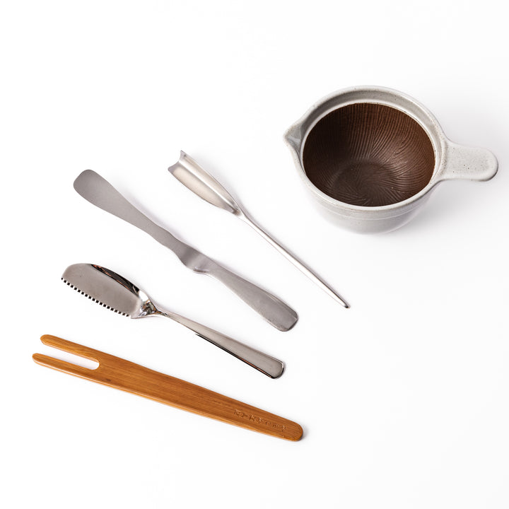 Japanese breakfast set featuring a ceramic suribachi mortar and pestle bowl with stainless steel butter knives and bamboo utensil, ideal for preparing and serving traditional morning dishes.