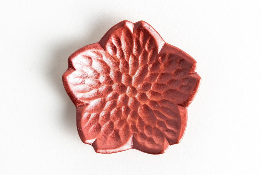 Red sakura-shaped lacquer dish with carved petal texture displayed on a white background.