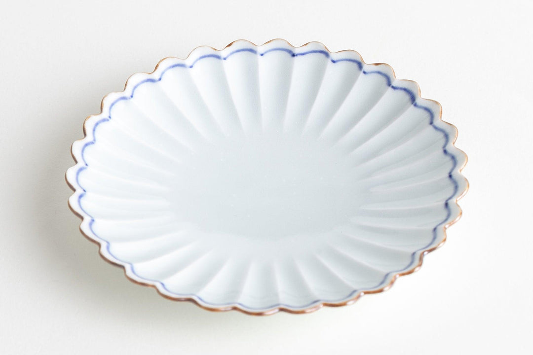 White chrysanthemum-shaped porcelain plate with scalloped rim and soft blue edge, ideal for serving small dishes.