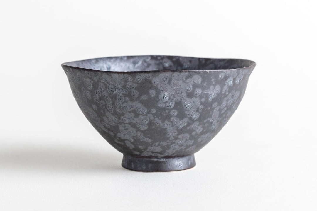 Black ceramic bowl with a mottled gray pattern and a gently flared rim, displayed against a white background.