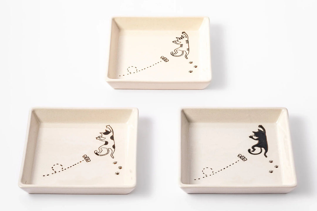 Square ceramic plates with playful cat and butterfly designs in three styles on a white background