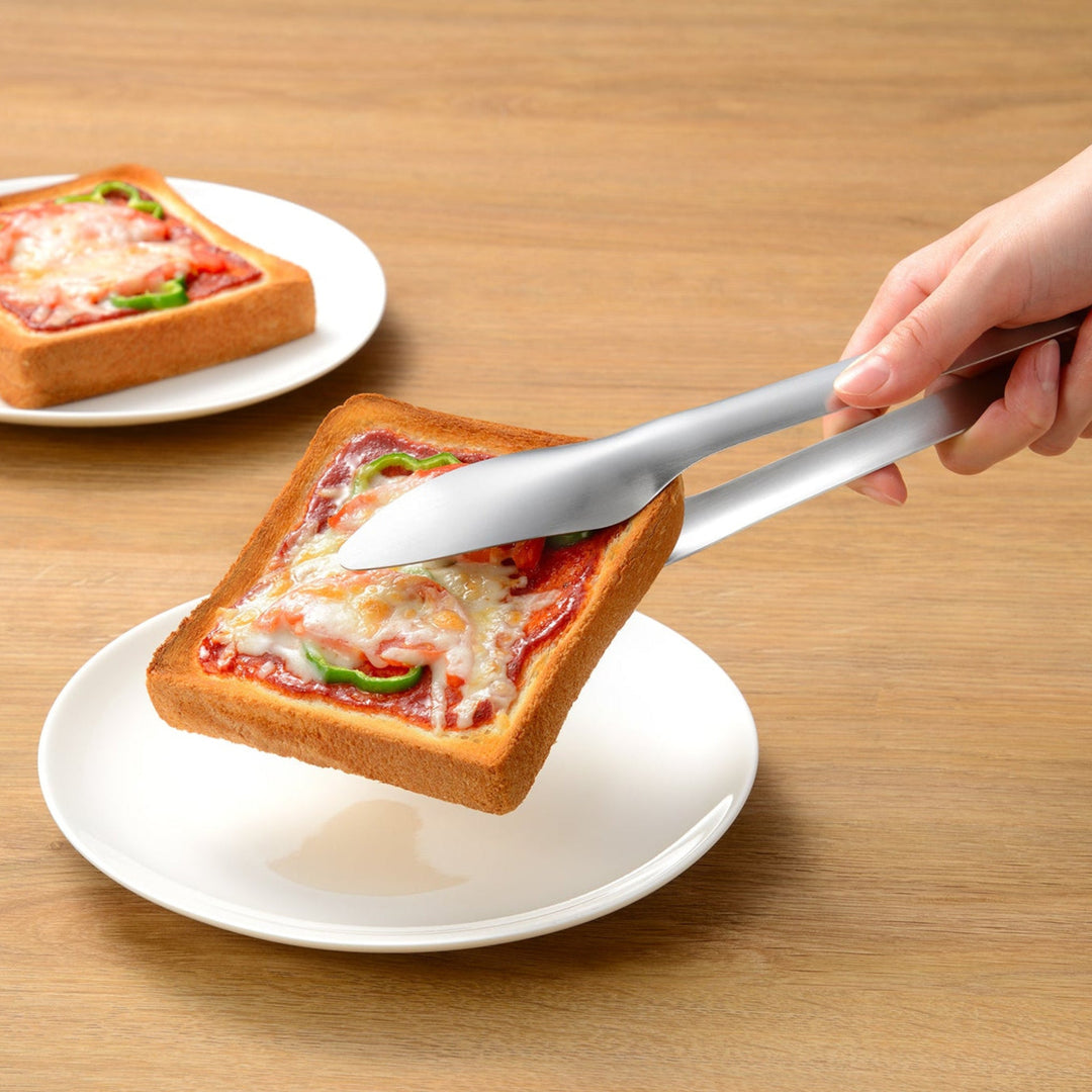 Japanese stainless steel bread tongs lifting a loaded pizza toast to show a secure grip without dropping toppings