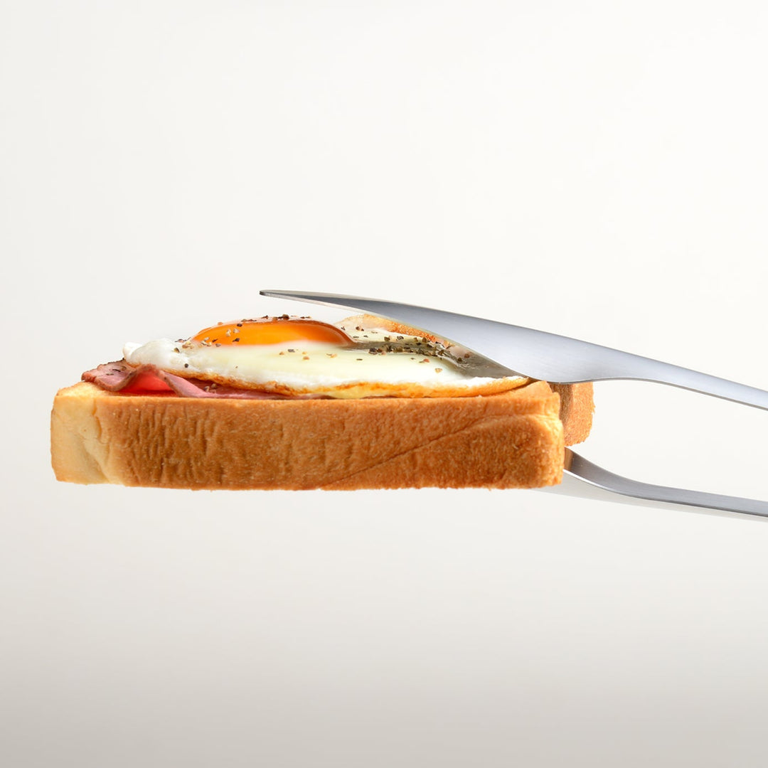 Professional stainless steel bread tongs holding a heavy ham and egg toast level to demonstrate superior stability