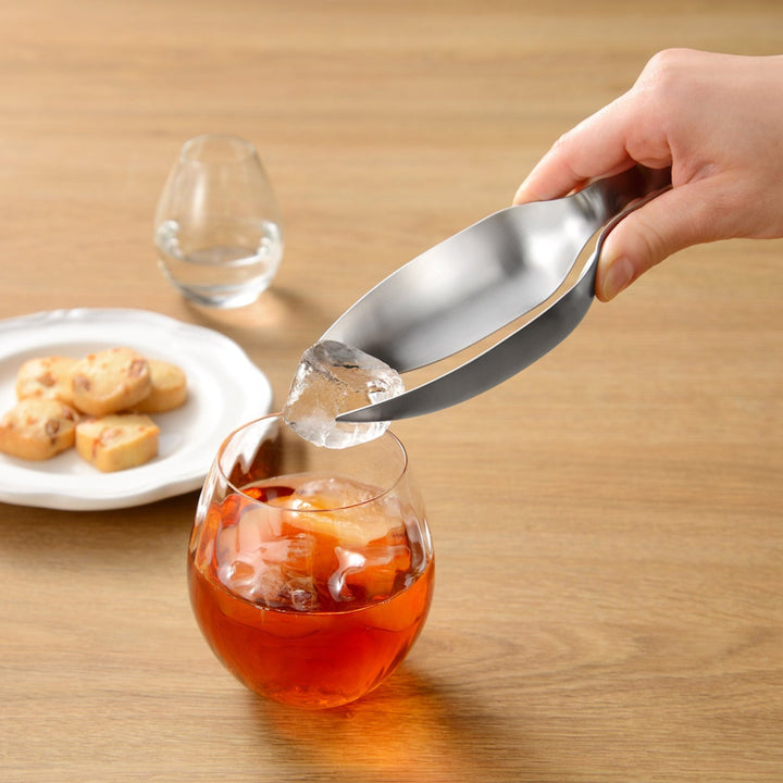 Japanese stainless steel tongs placing a single ice cube into a glass of iced tea to demonstrate precision control