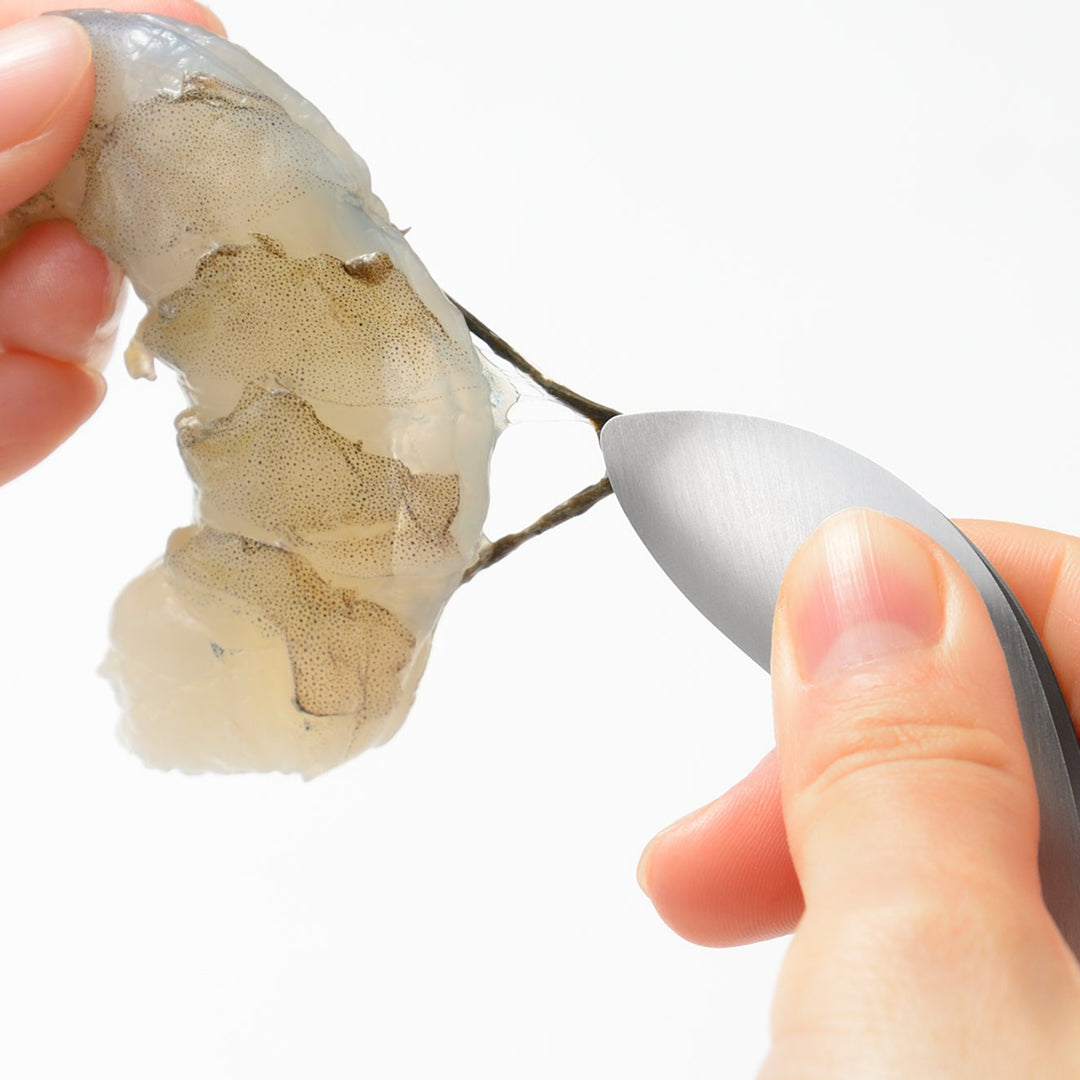 Japanese stainless steel fingertip tongs removing the vein from a raw shrimp showing extreme precision and control