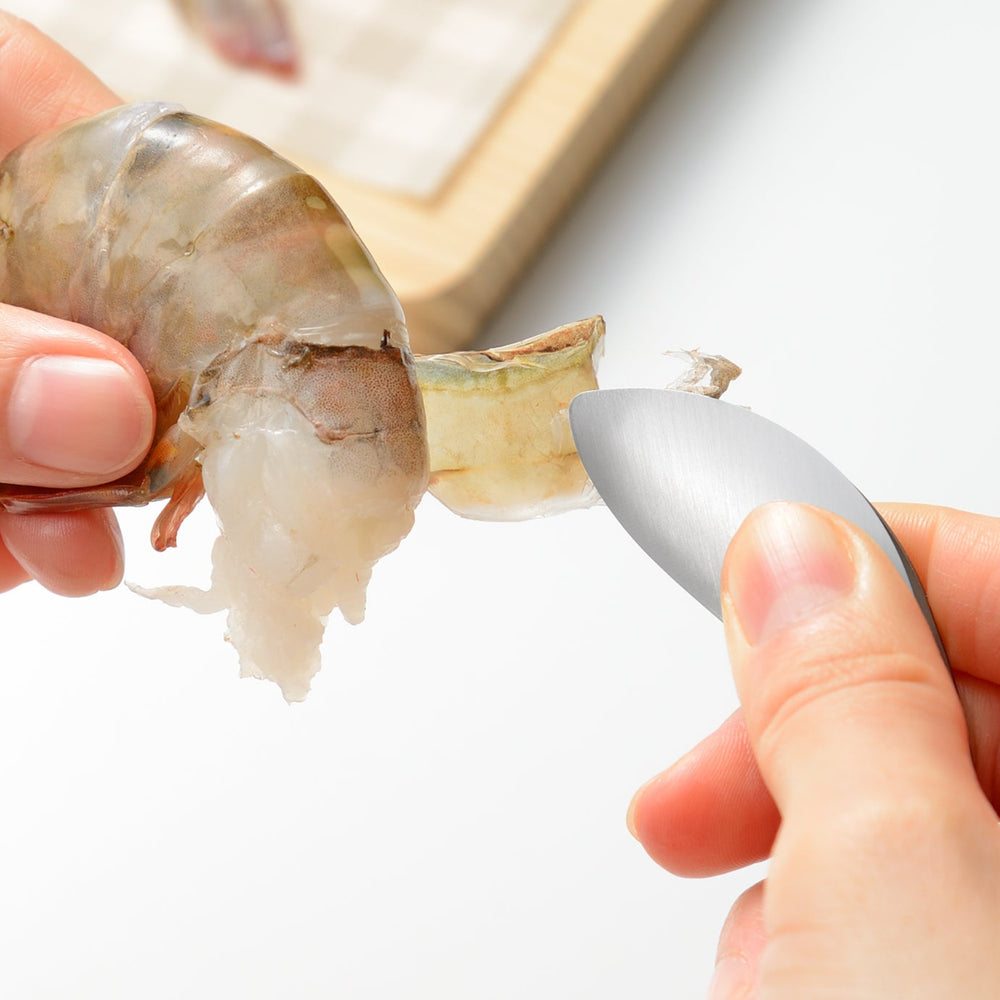 Precision stainless steel tongs peeling the shell off a raw shrimp illustrating how to handle slippery seafood easily