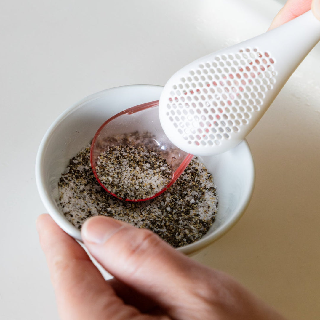 Nami scooping salt and pepper seasoning blend from white bowl with spice maraca sifter spoon kitchen cooking utensil