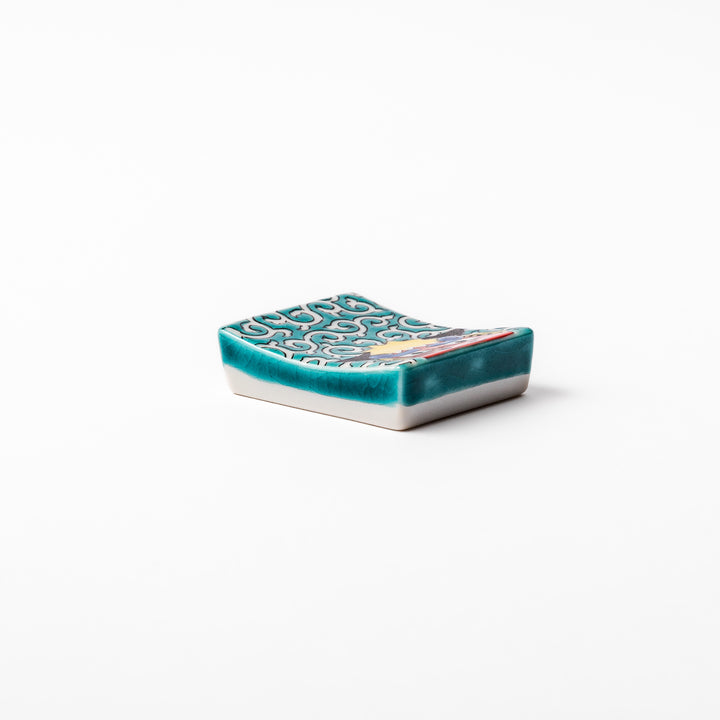 Rectangular Japanese ceramic chopstick rest featuring a bold red lion dance motif with green swirl background, adding festive tradition to dining tables.