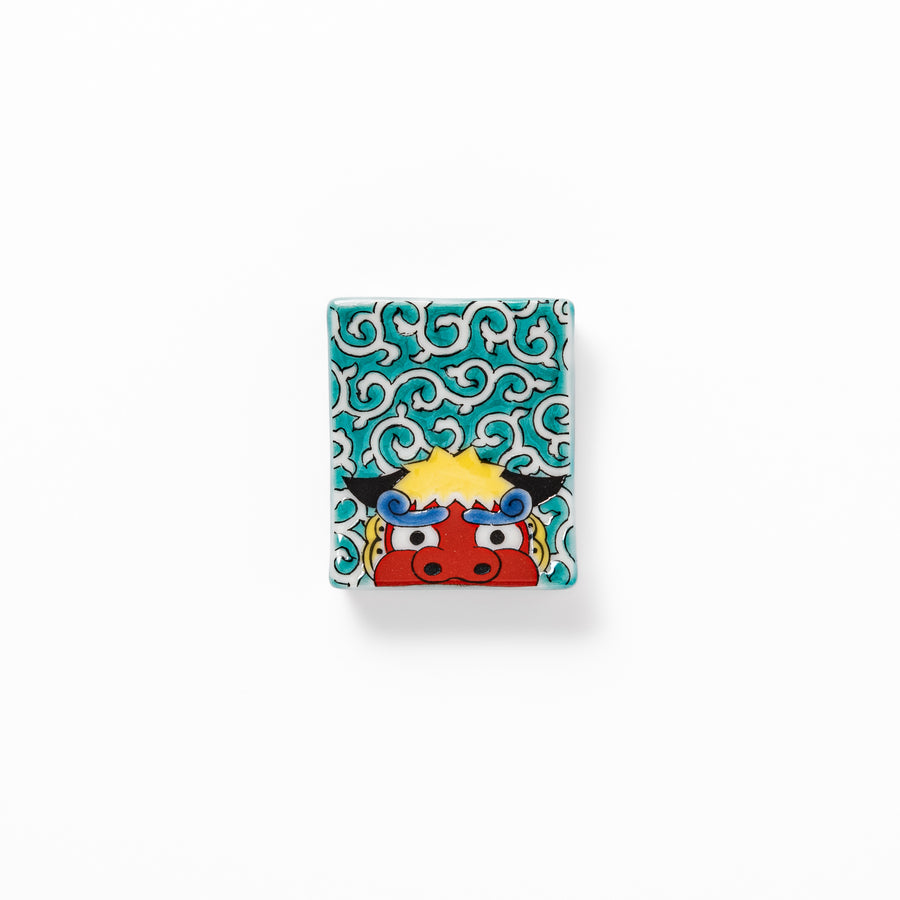Rectangular Japanese ceramic chopstick rest featuring a bold red lion dance motif with green swirl background, adding festive tradition to dining tables.