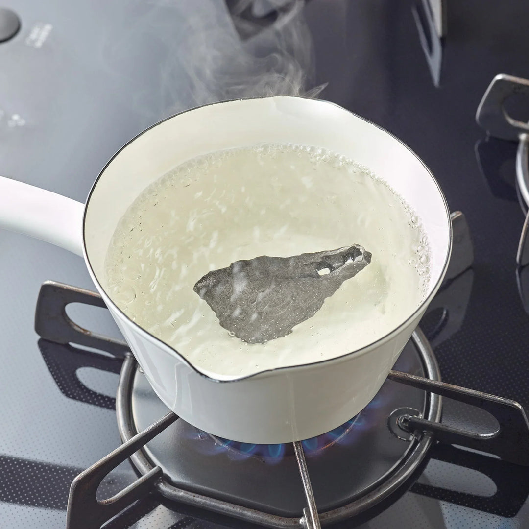Bird shaped cast iron supplement resting inside a pot of boiling water on a gas stovetop