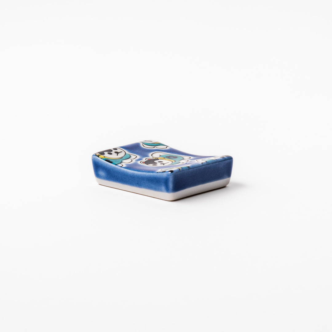 Rectangular Japanese ceramic chopstick rest with a deep blue background decorated with playful lucky dog motifs, bringing charm and fun to dining tables.