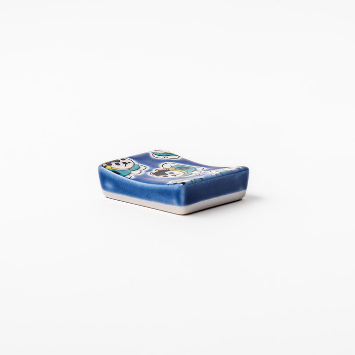 Rectangular Japanese ceramic chopstick rest with a deep blue background decorated with playful lucky dog motifs, bringing charm and fun to dining tables.