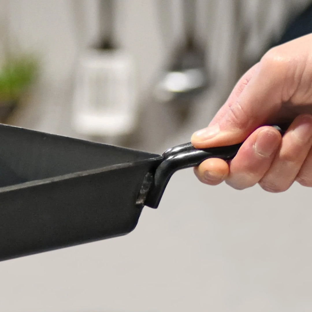 Person holding a square compact deep frying pan showing the sturdy welded iron handle attachment