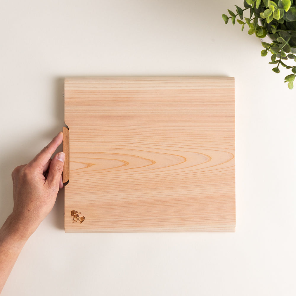 Medium Hinoki wood cutting board with natural grain, side handle, engraved motif, and smooth finish, crafted in Japan