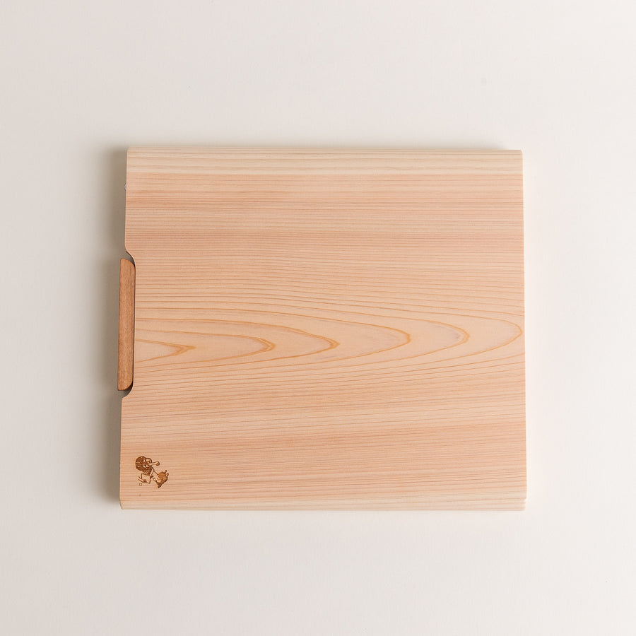 Medium Hinoki wood cutting board with natural grain, side handle, engraved motif, and smooth finish, crafted in Japan