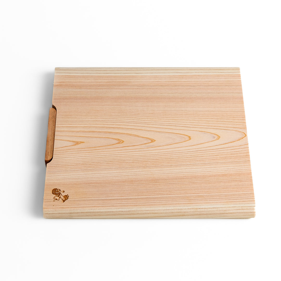 Medium Hinoki wood cutting board with natural grain, side handle, engraved motif, and smooth finish, crafted in Japan