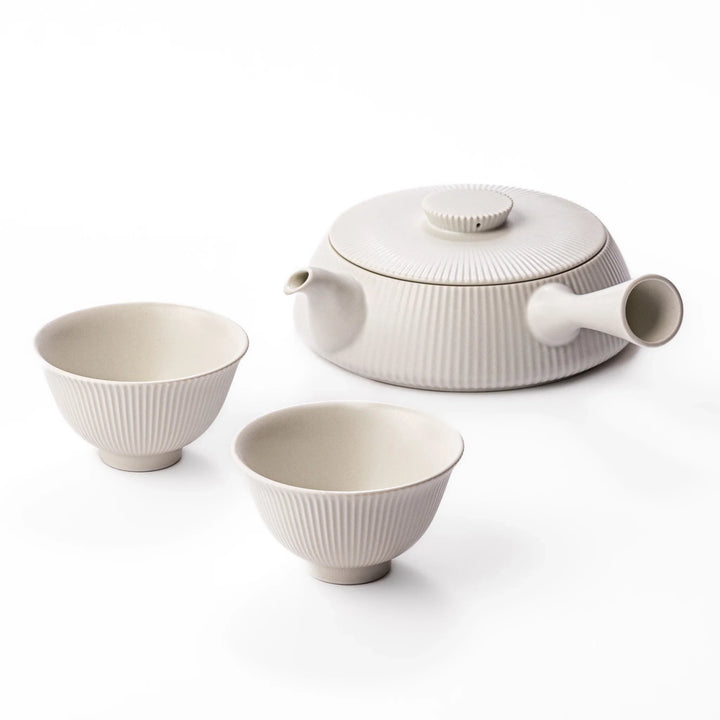 Minimalist Japanese tea set with ribbed white kyusu teapot and two cups for serene modern tea enjoyment.