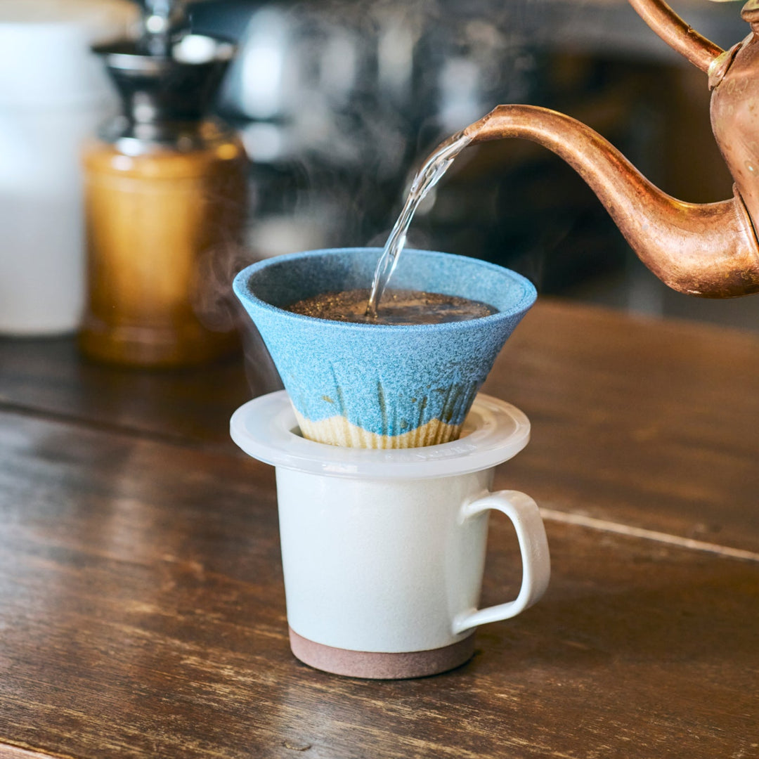 Handmade Mount Fuji shaped ceramic coffee filter in sky blue glaze, capturing the warmth of a peaceful pour over coffee ritual.