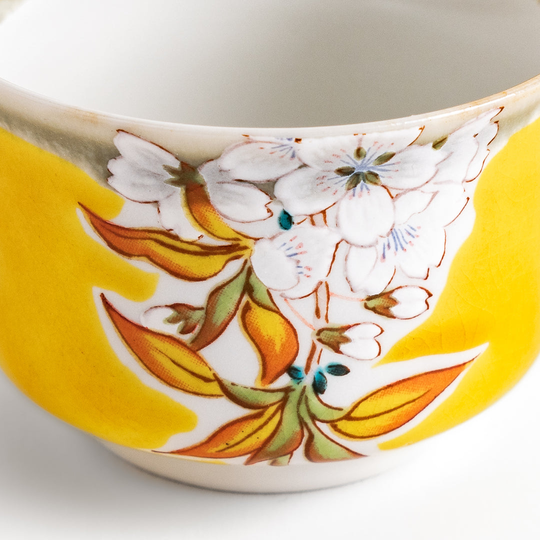 Yellow sake cup with a delicate cherry blossom design, perfectly complementing spring-themed tableware for a vibrant and charming dining experience.