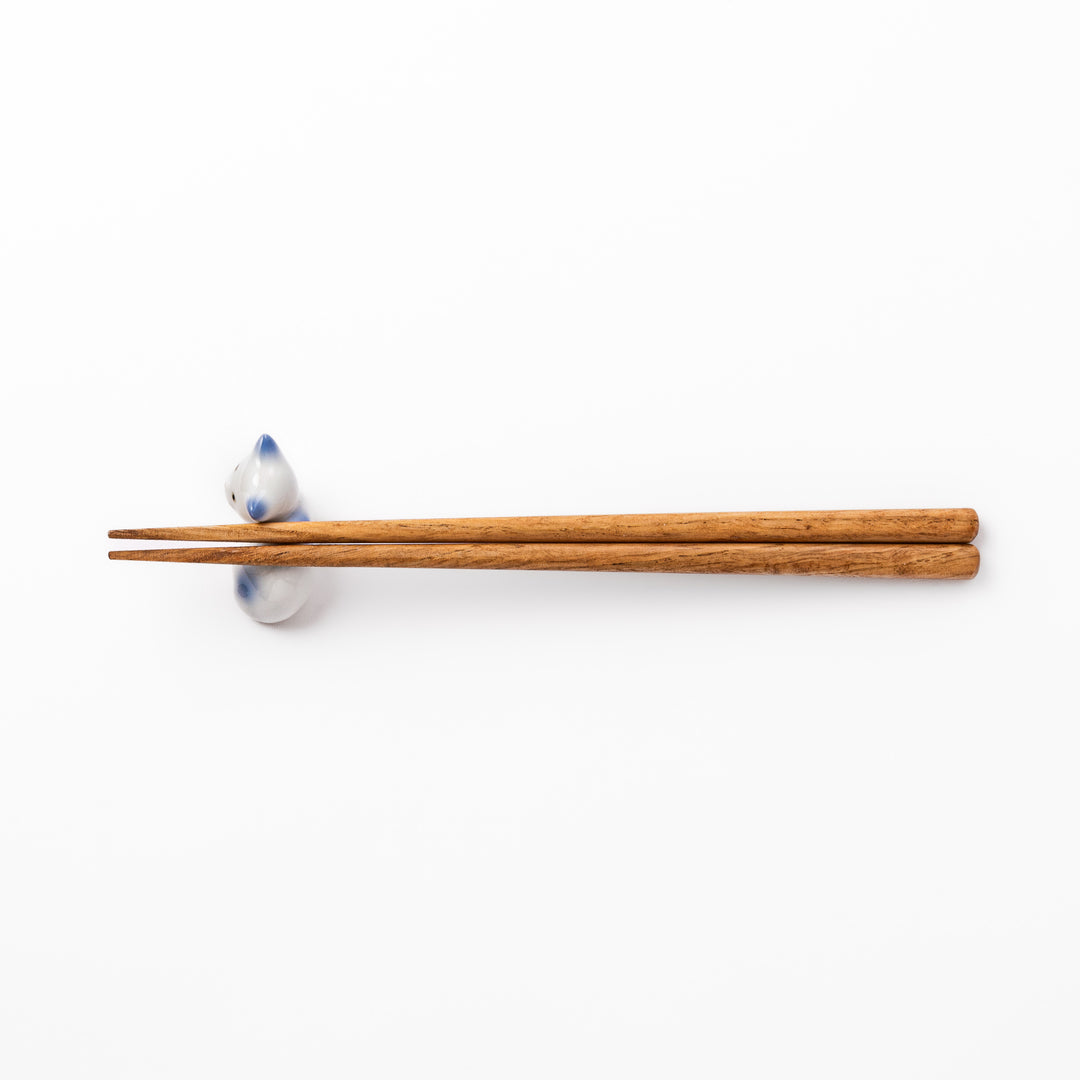 White ceramic chopstick rest shaped like a reclining cat with soft blue accents and a glossy finish.