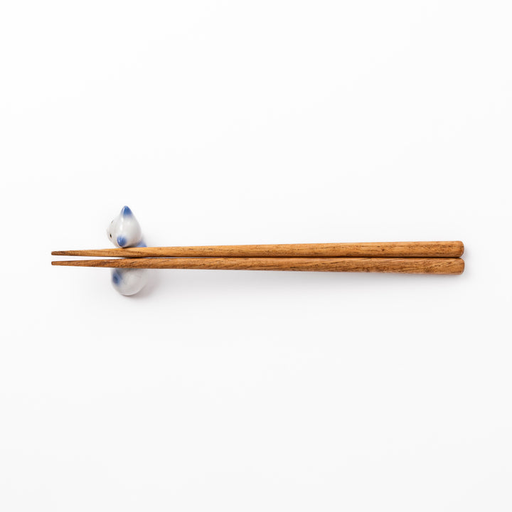 White ceramic chopstick rest shaped like a reclining cat with soft blue accents and a glossy finish.