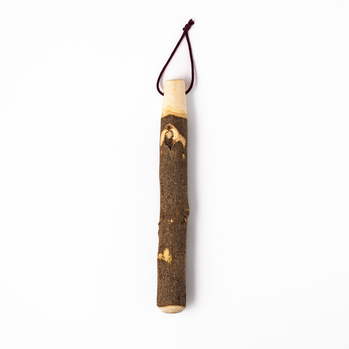 Natural sansho wood pestle featuring bark textures and a burgundy hanging cord, ideal for traditional Japanese grinding.