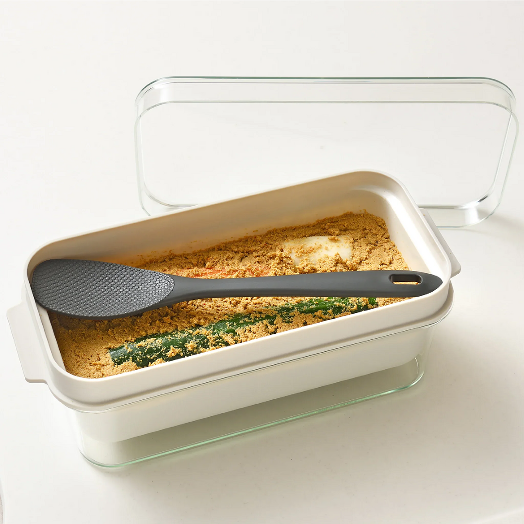 Japanese nukadoko fermentation box with rice bran bed and mixing spatula, perfect for making homemade pickled vegetables.