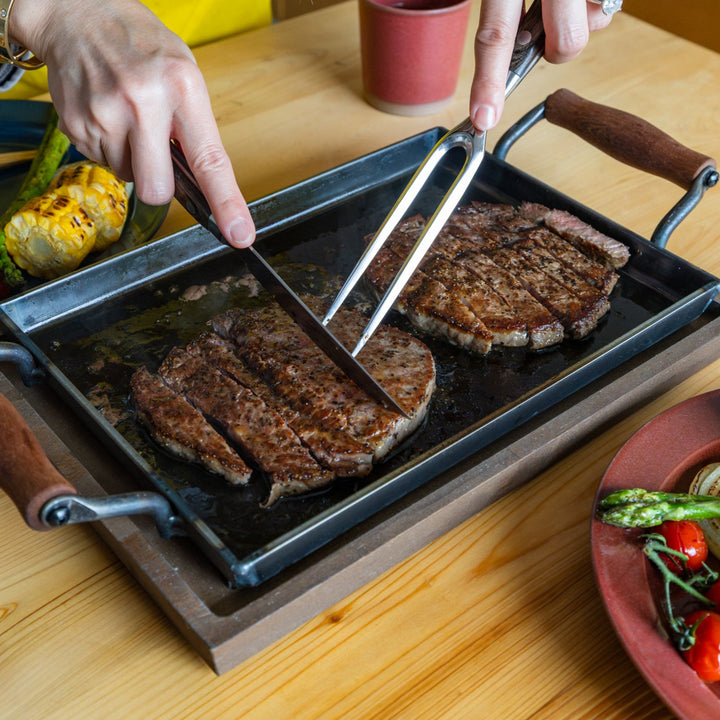 Nami slicing juicy grilled beef steak meat on aux japanese cast iron griddle with lid dining table barbecue platter