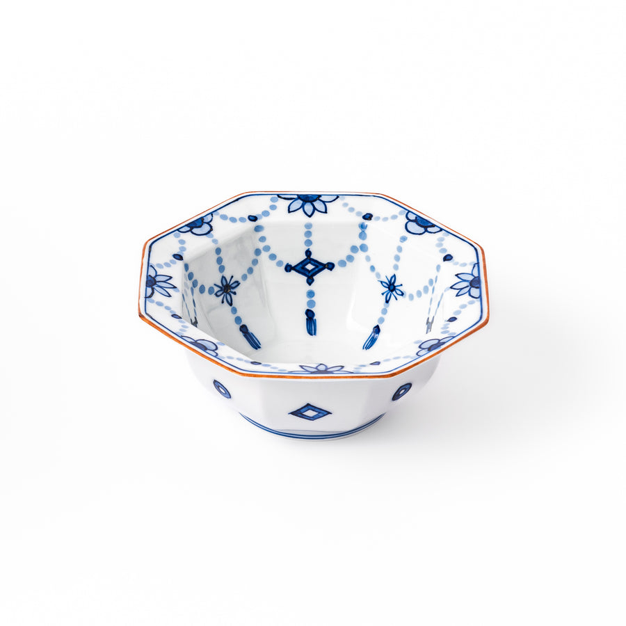 White octagonal dessert bowl with blue floral garland patterns and a red-rimmed edge, featuring intricate geometric detailing.