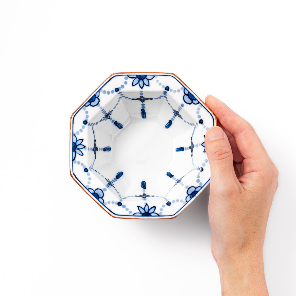 White octagonal dessert bowl with blue floral garland patterns and a red-rimmed edge, featuring intricate geometric detailing.