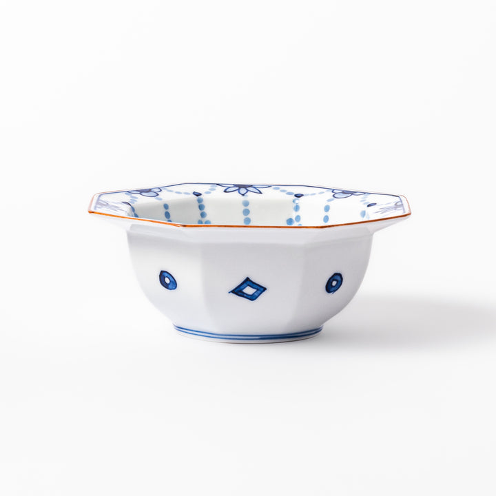 White octagonal dessert bowl with blue floral garland patterns and a red-rimmed edge, featuring intricate geometric detailing.