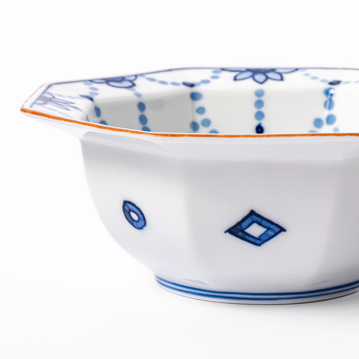 White octagonal dessert bowl with blue floral garland patterns and a red-rimmed edge, featuring intricate geometric detailing.
