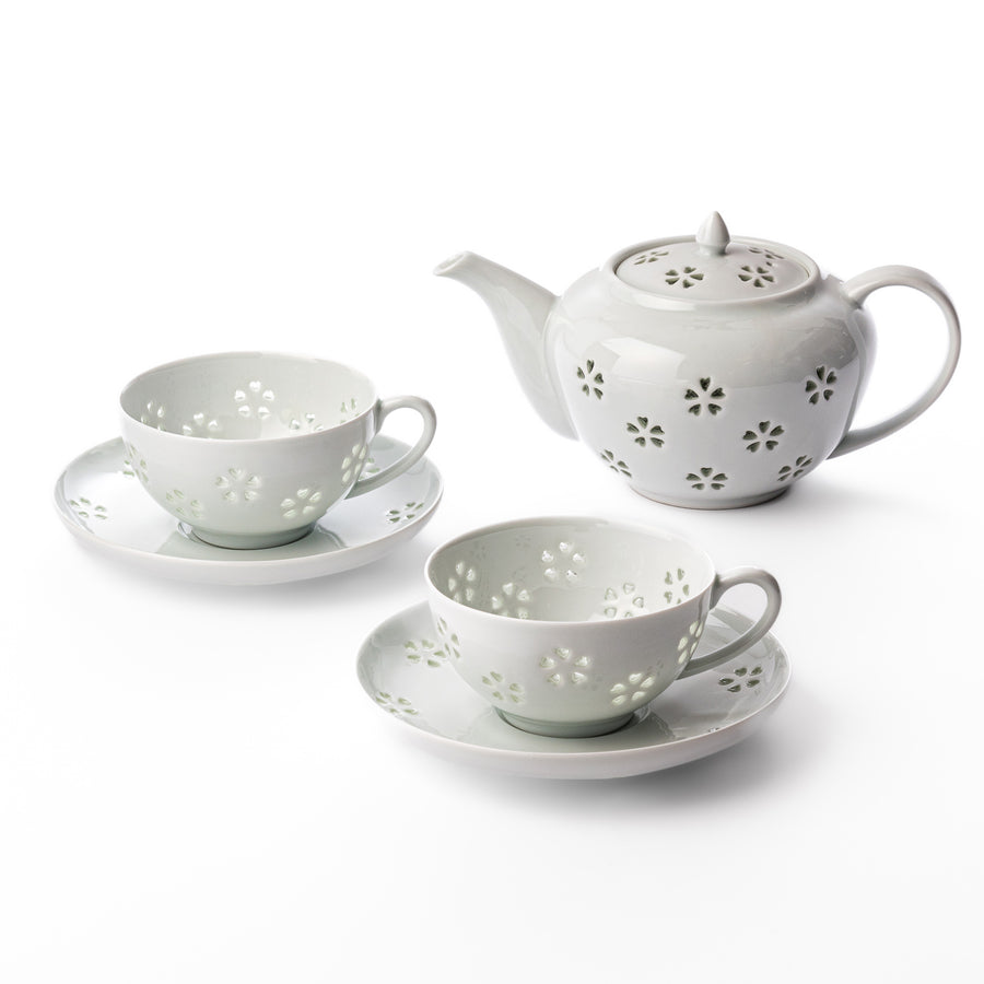 Japanese porcelain tea set featuring a teapot and two teacups with matching saucers, delicately decorated with translucent petal cutouts for an elegant and serene tea experience.