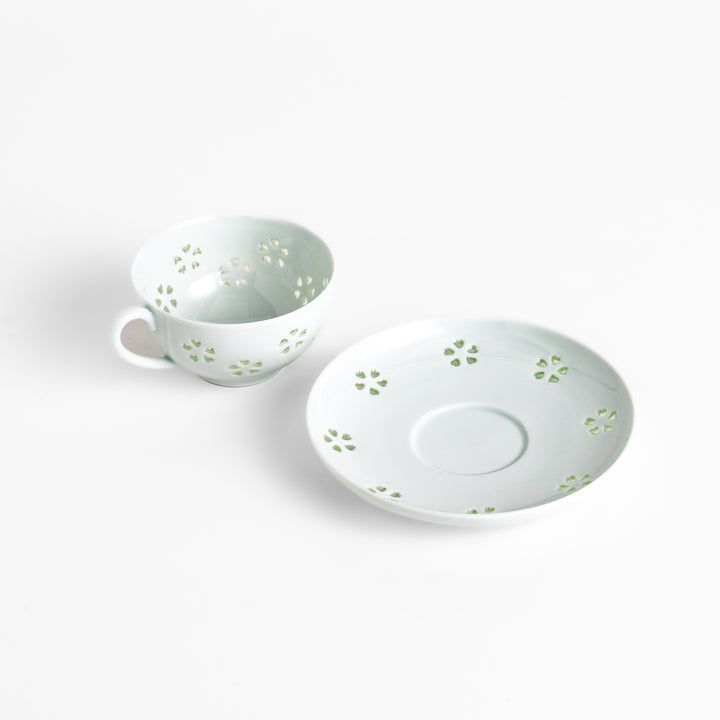 Delicate teacup and saucer set featuring intricate petal-shaped cutouts, allowing light to pass through, creating a soft, elegant design in pale green and white porcelain.