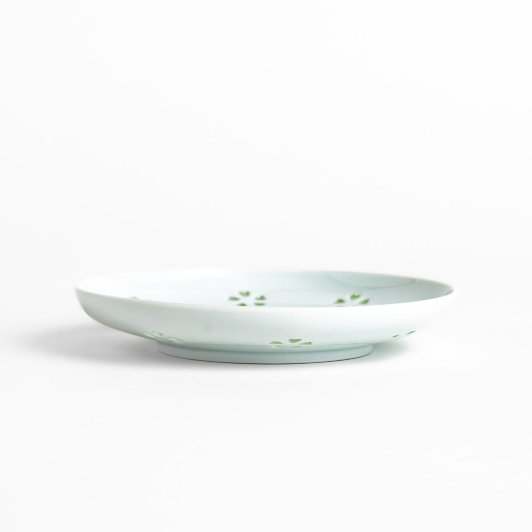 Delicate teacup and saucer set featuring intricate petal-shaped cutouts, allowing light to pass through, creating a soft, elegant design in pale green and white porcelain.