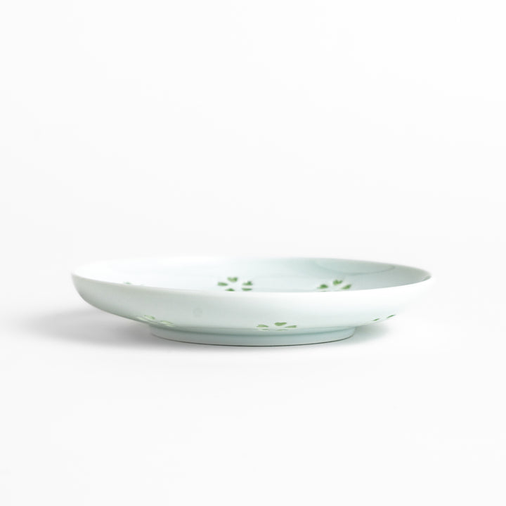 Delicate teacup and saucer set featuring intricate petal-shaped cutouts, allowing light to pass through, creating a soft, elegant design in pale green and white porcelain.
