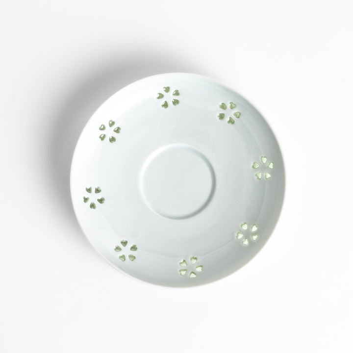 Delicate teacup and saucer set featuring intricate petal-shaped cutouts, allowing light to pass through, creating a soft, elegant design in pale green and white porcelain.