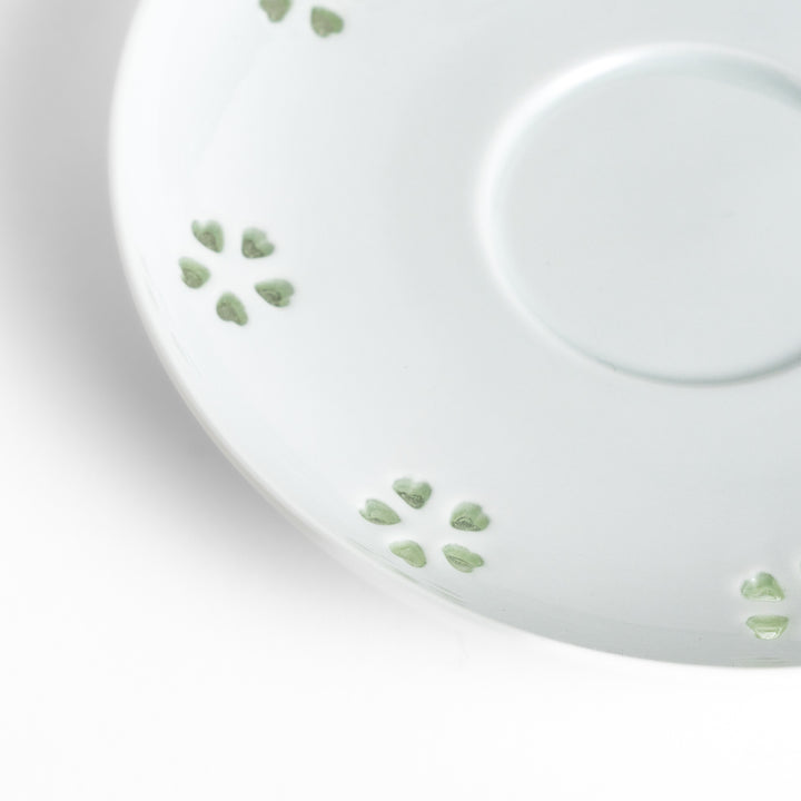 Delicate teacup and saucer set featuring intricate petal-shaped cutouts, allowing light to pass through, creating a soft, elegant design in pale green and white porcelain.