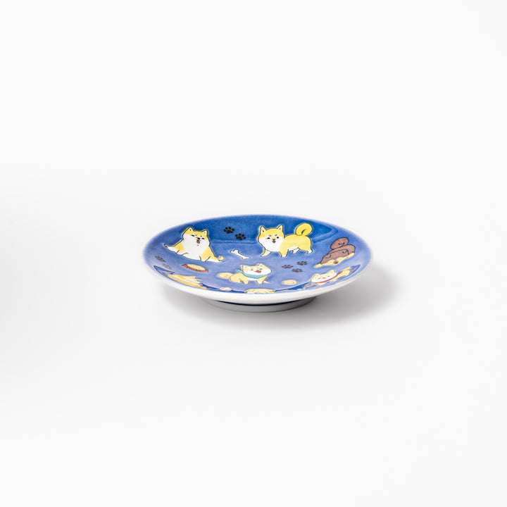 Round Japanese ceramic sauce dish with a deep blue background decorated with playful Shiba Inu dogs, paw prints, and bones, perfect for condiments or snacks.