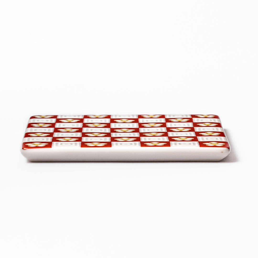 Square Japanese ceramic coaster with red and white checkered pattern decorated with plum blossom motifs, adding traditional charm to any dining table.