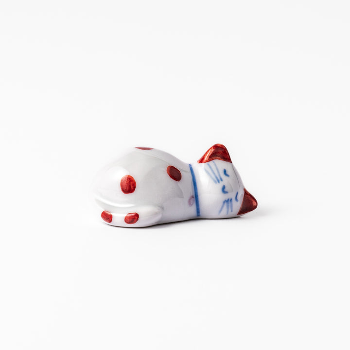 Red polka-dot ceramic cat chopstick rest in a sleeping pose, featuring hand-painted details and a glossy finish to add playful charm to your table setting.