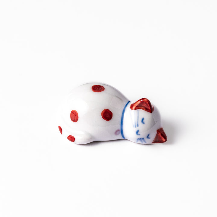 Red polka-dot ceramic cat chopstick rest in a sleeping pose, featuring hand-painted details and a glossy finish to add playful charm to your table setting.