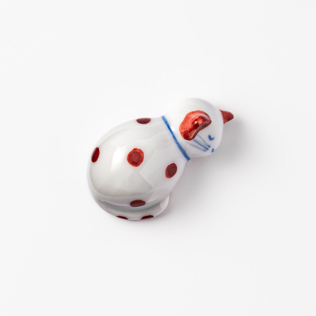 Red polka-dot ceramic cat chopstick rest in a sleeping pose, featuring hand-painted details and a glossy finish to add playful charm to your table setting.