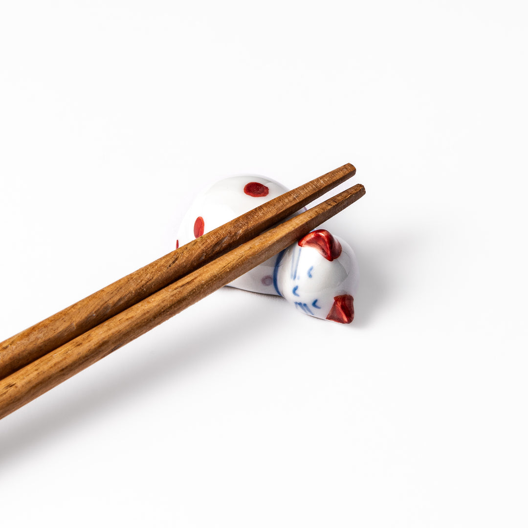 Red polka-dot ceramic cat chopstick rest in a sleeping pose, featuring hand-painted details and a glossy finish to add playful charm to your table setting.