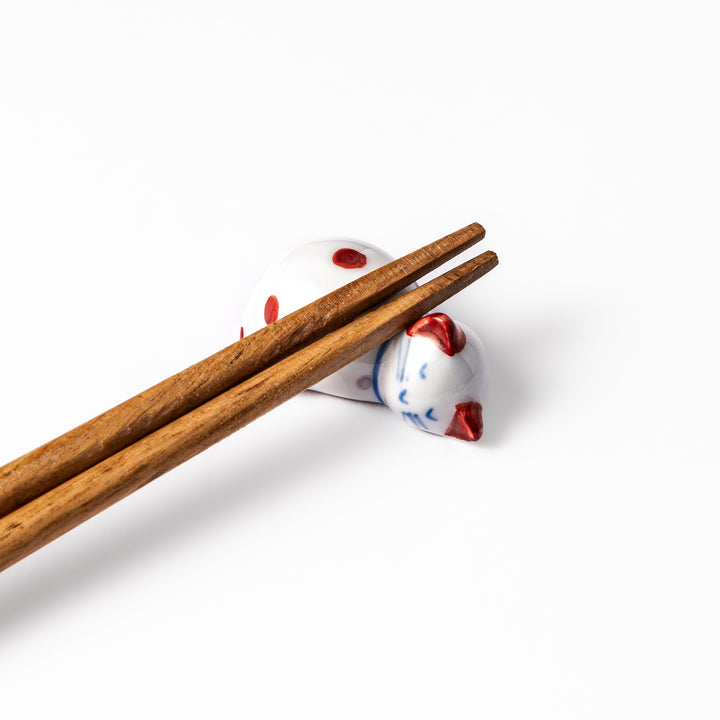 Red polka-dot ceramic cat chopstick rest in a sleeping pose, featuring hand-painted details and a glossy finish to add playful charm to your table setting.